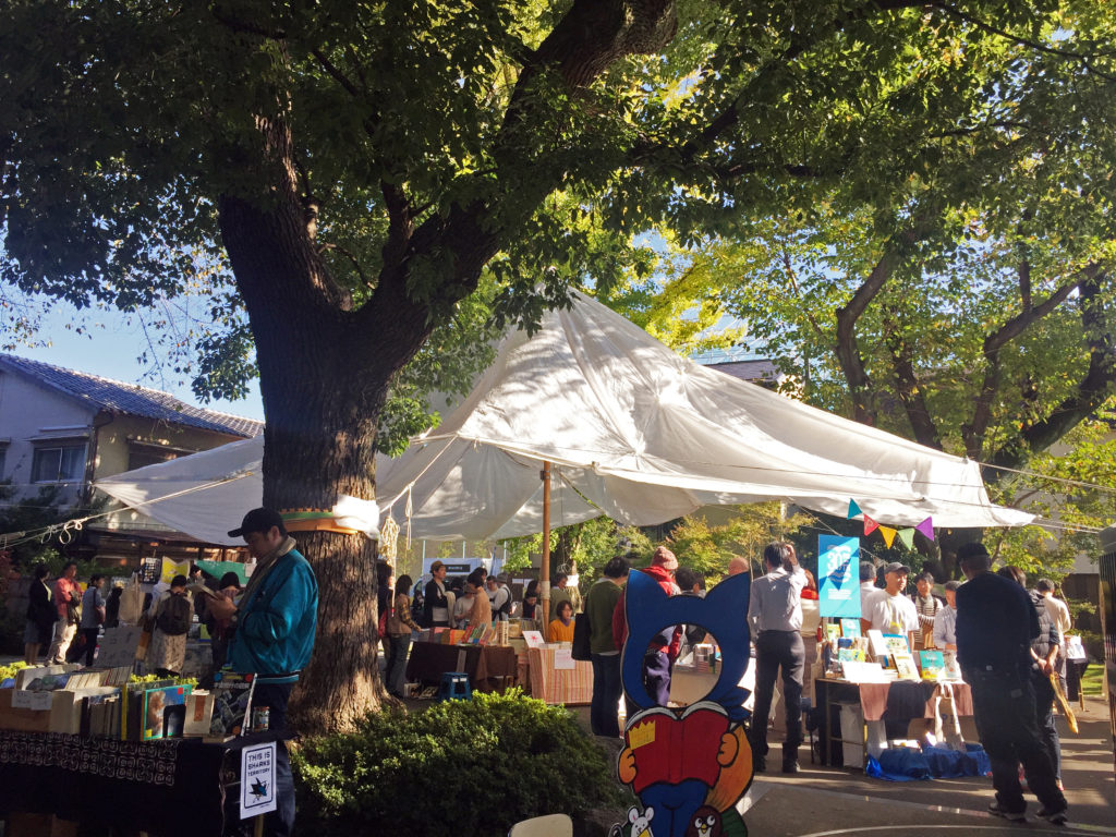 大きなパラソルの下に本好きが大集合！「しのばずくんの本の縁日」